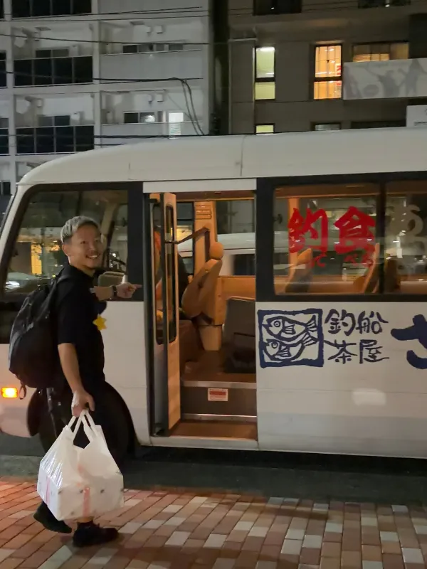 お迎えのバスの前で笑顔のメンバー